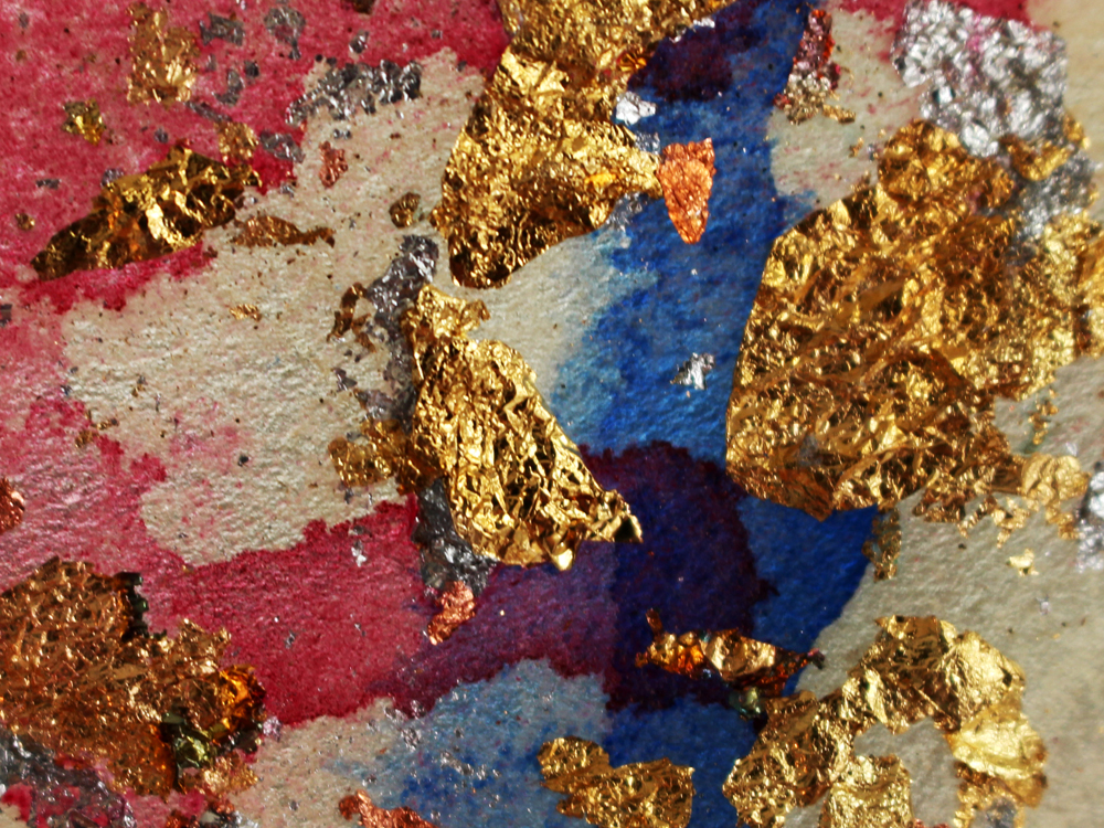 A close up photo of a piece of rawhide stained with red and blue, with gold and silver leaf attached.