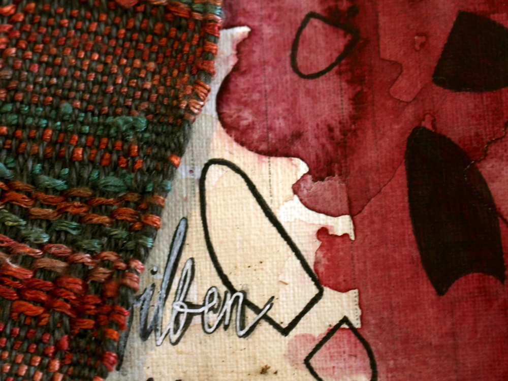 A close up photo of a collage. The bottom layer is a textured paper with stains of red paint, black drawn shoeprints and text, partially covered by a orange-teal fabric with a rough weave. 